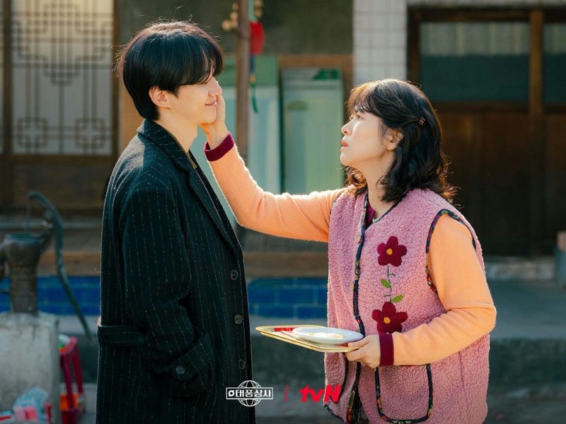people-young man-gentle smile-motherly woman-affectionate touch-Korean drama setting-outdoor scene