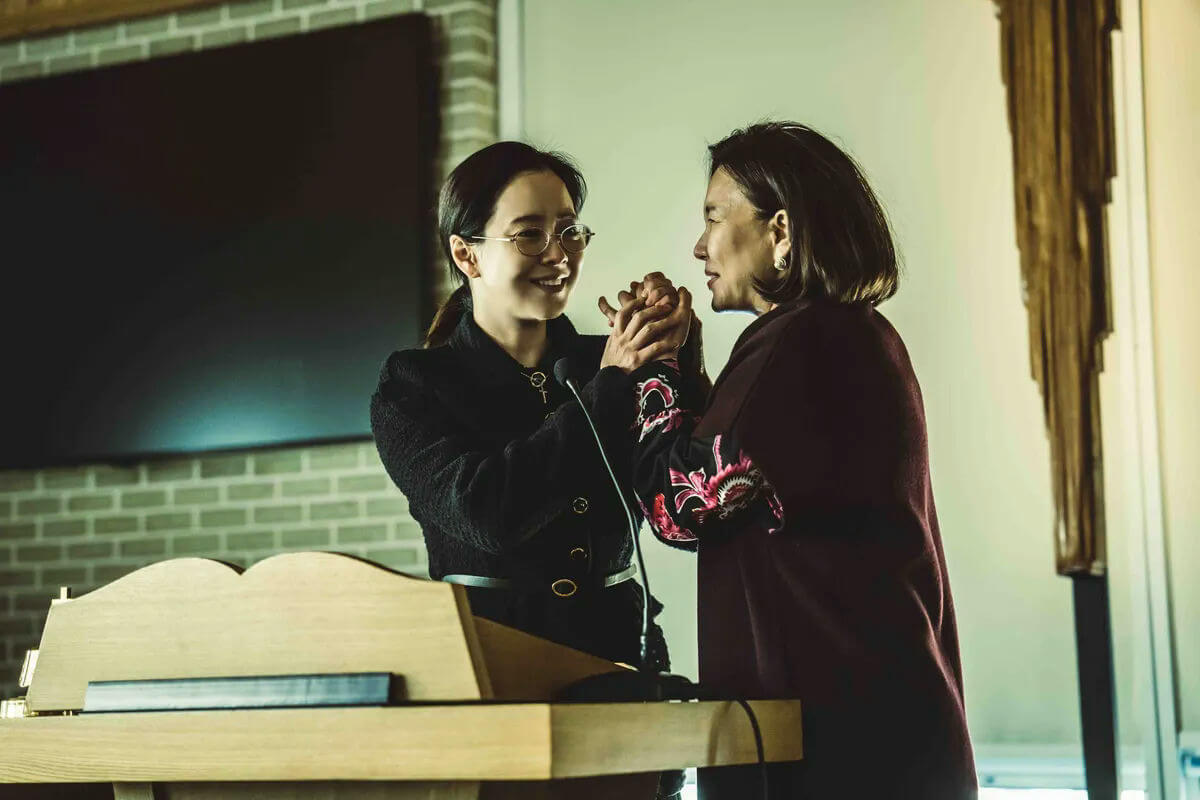 people-Two women-A-Holding hands-A-Smiling-B-Dark clothing-C-Podium