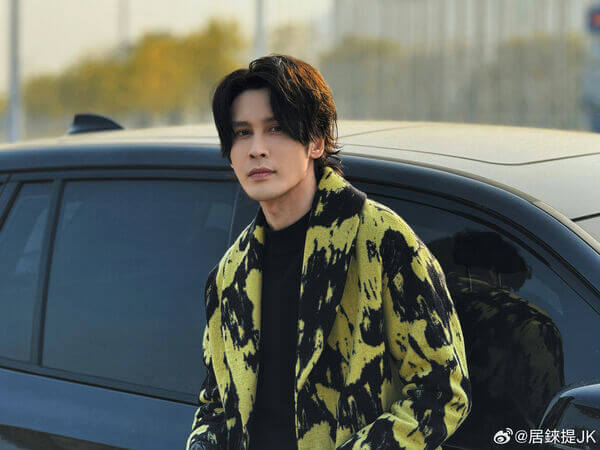 people-man-A-yellow and black coat-A-dark hair-A-standing by a car-A-outdoor setting