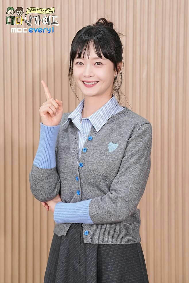 people-woman-smiling-pointing up-gray cardigan-blue accents-striped shirt-MBC Every1 logo
