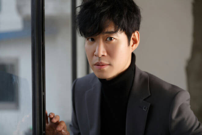 people-man-A-black turtleneck-B-grey blazer-C-standing near window