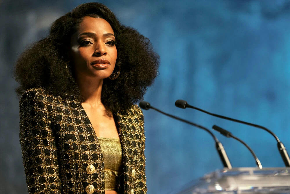 people-woman-A-speaking-A-stage-A-black and gold jacket-A-microphone-A-blue background