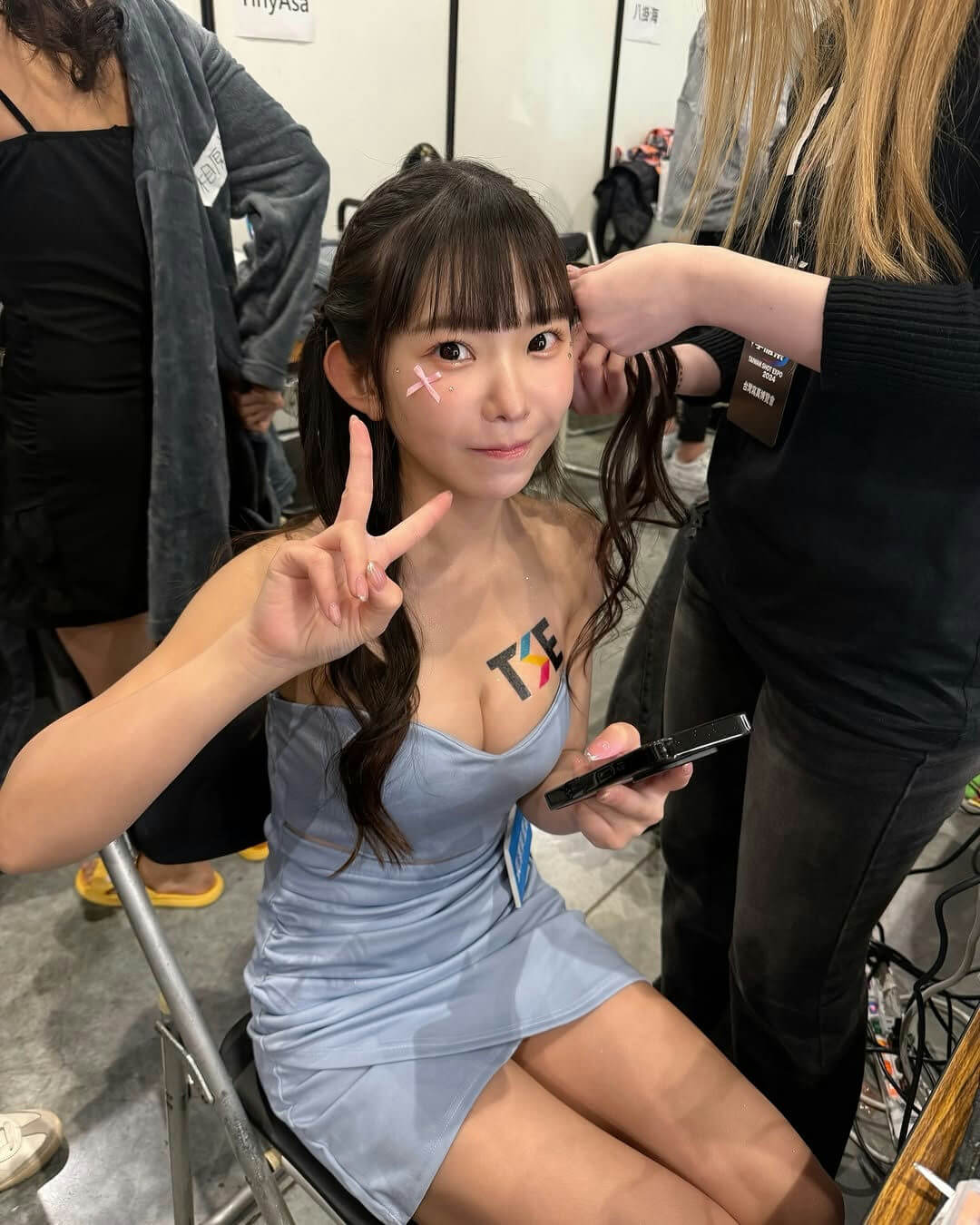 people-young East Asian woman-A-light blue strapless dress-B-making peace sign-C-getting hair styled