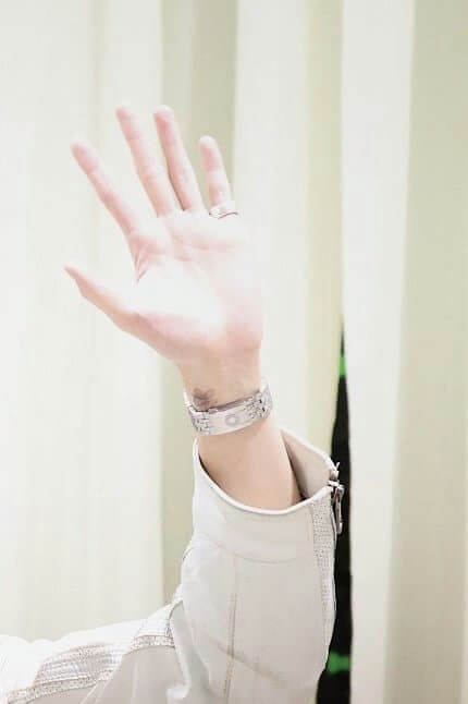 people-hand raised-A-white sleeve-A-silver bracelet-B-small dark tattoo-C
