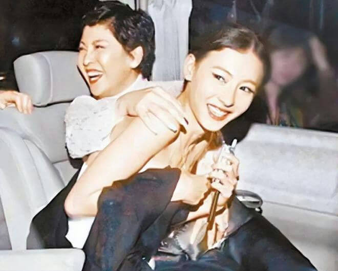 people-Two women-A-laughing-A-embracing-B-inside a car-B-holding a small object