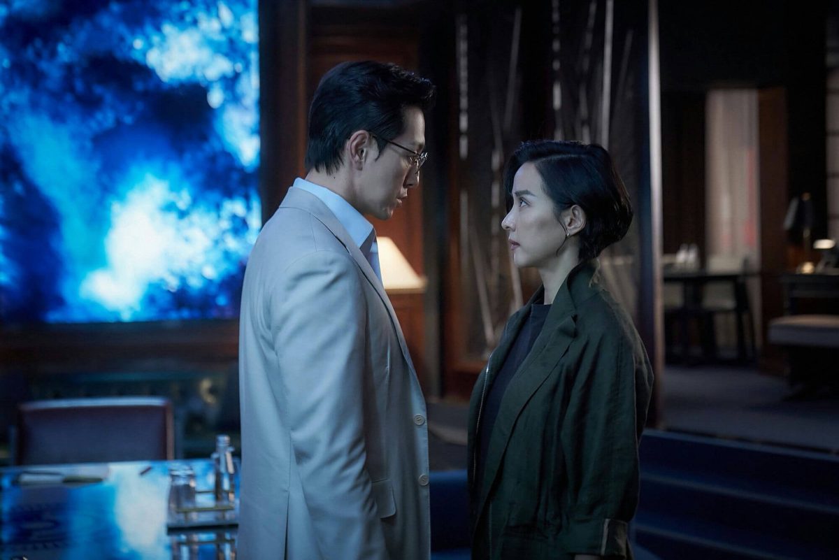 people-man in light suit-woman in dark jacket-intense gaze-blue screen background-indoor setting