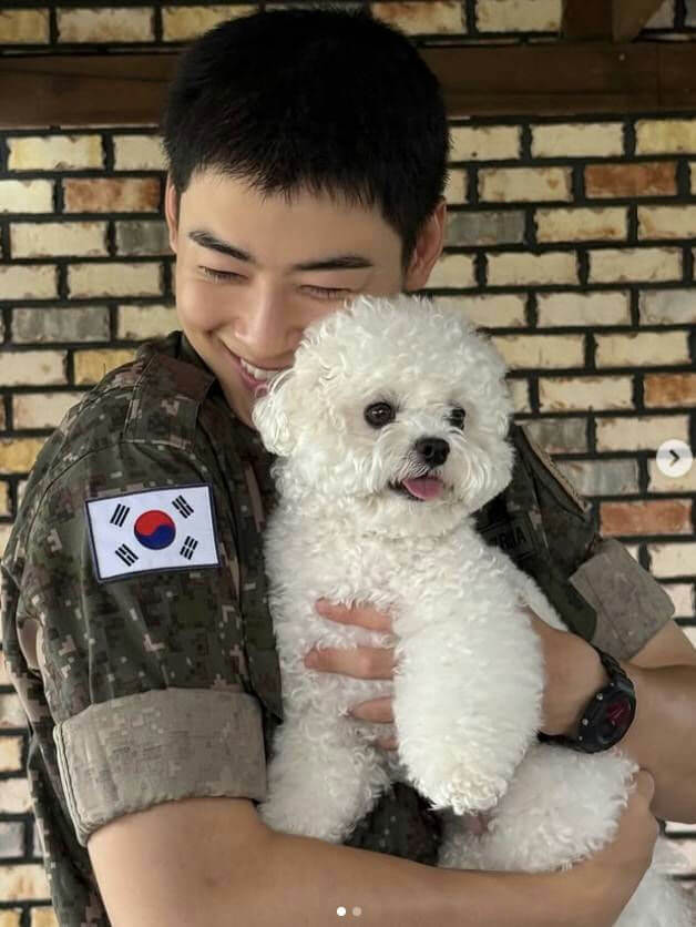 person-A-smiling-A-military uniform-A-holding-A-dog-A-Bichon Frise