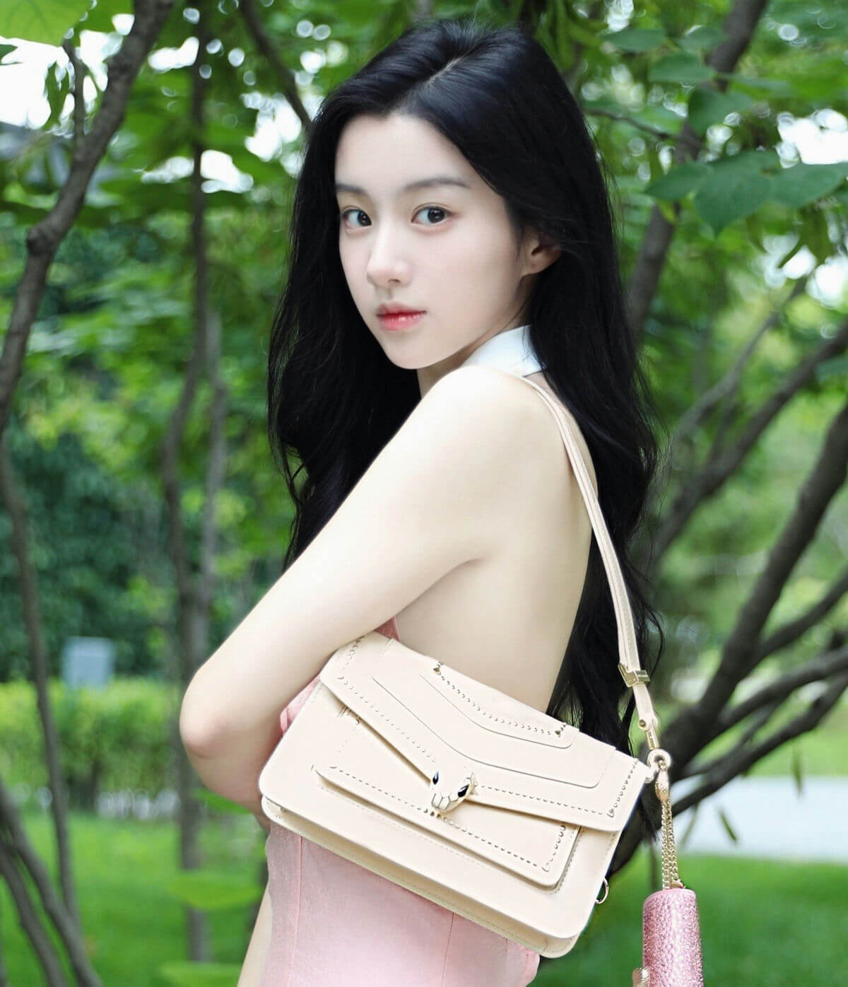 people-young woman-A-black hair-A-pink dress-A-beige shoulder bag-A-outdoor setting