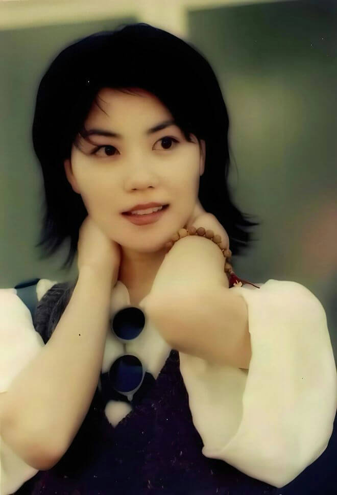 people-Faye Wong-1990s-A-short black hair-A-white blouse with dark vest-B-wooden bead bracelet-C-sunglasses hanging on shirt