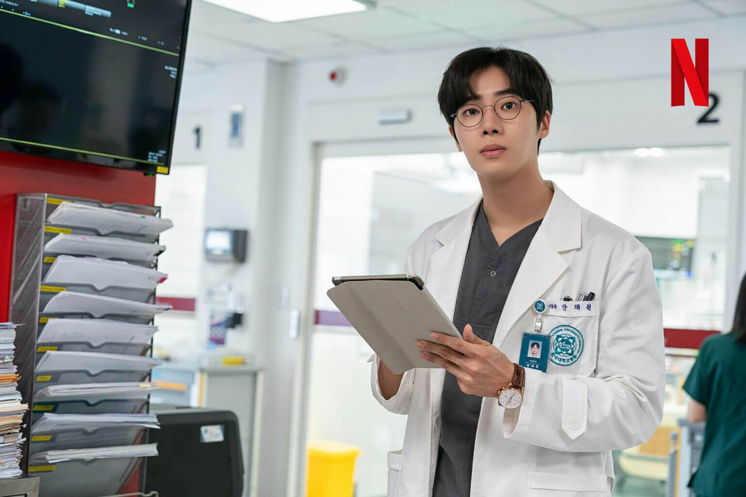 people-A-doctor-A-man-A-hospital-B-holding tablet-B-white lab coat-C-Netflix logo