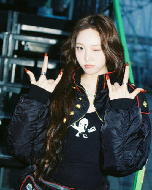 people-woman-winking-black bomber jacket-skull graphic tank top-long wavy brown hair-red long nails