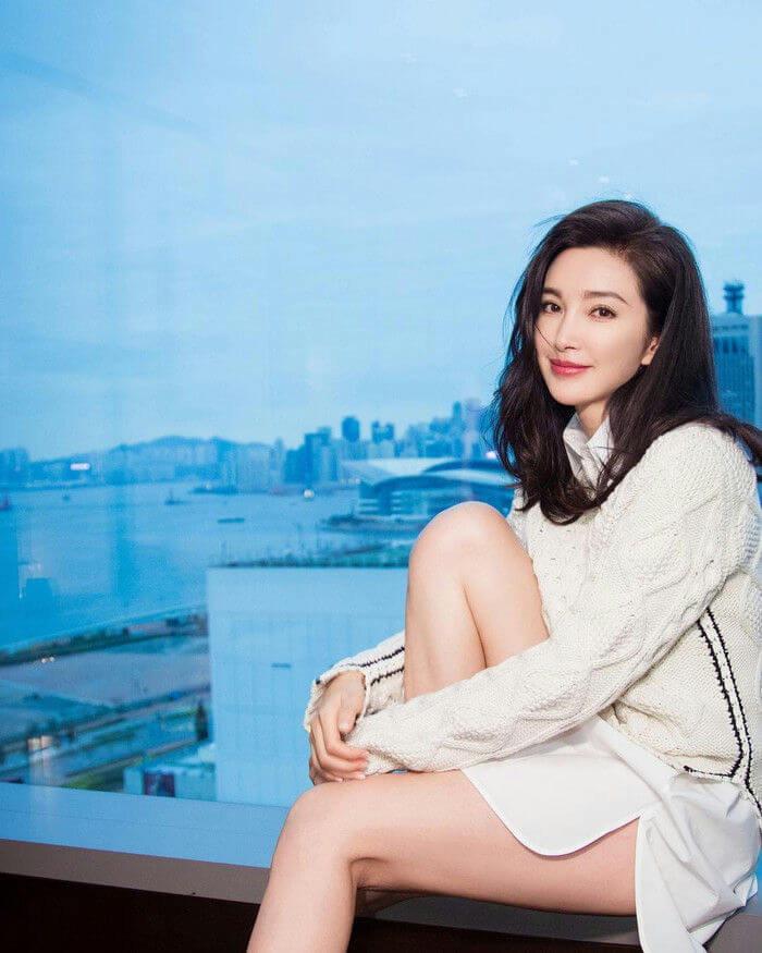 people-A-woman-A-smiling-A-sitting-A-white sweater-B-black hair-B-cityscape view-C