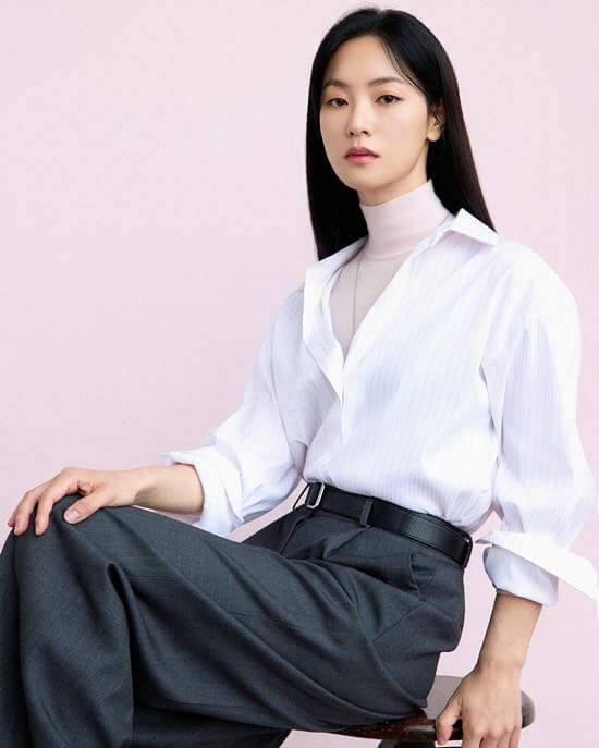 people-A-woman-A-Korean-A-long black hair-A-white button-down shirt-A-light pink turtleneck-A-dark gray trousers-A-black belt-A-sitting-A-studio portrait