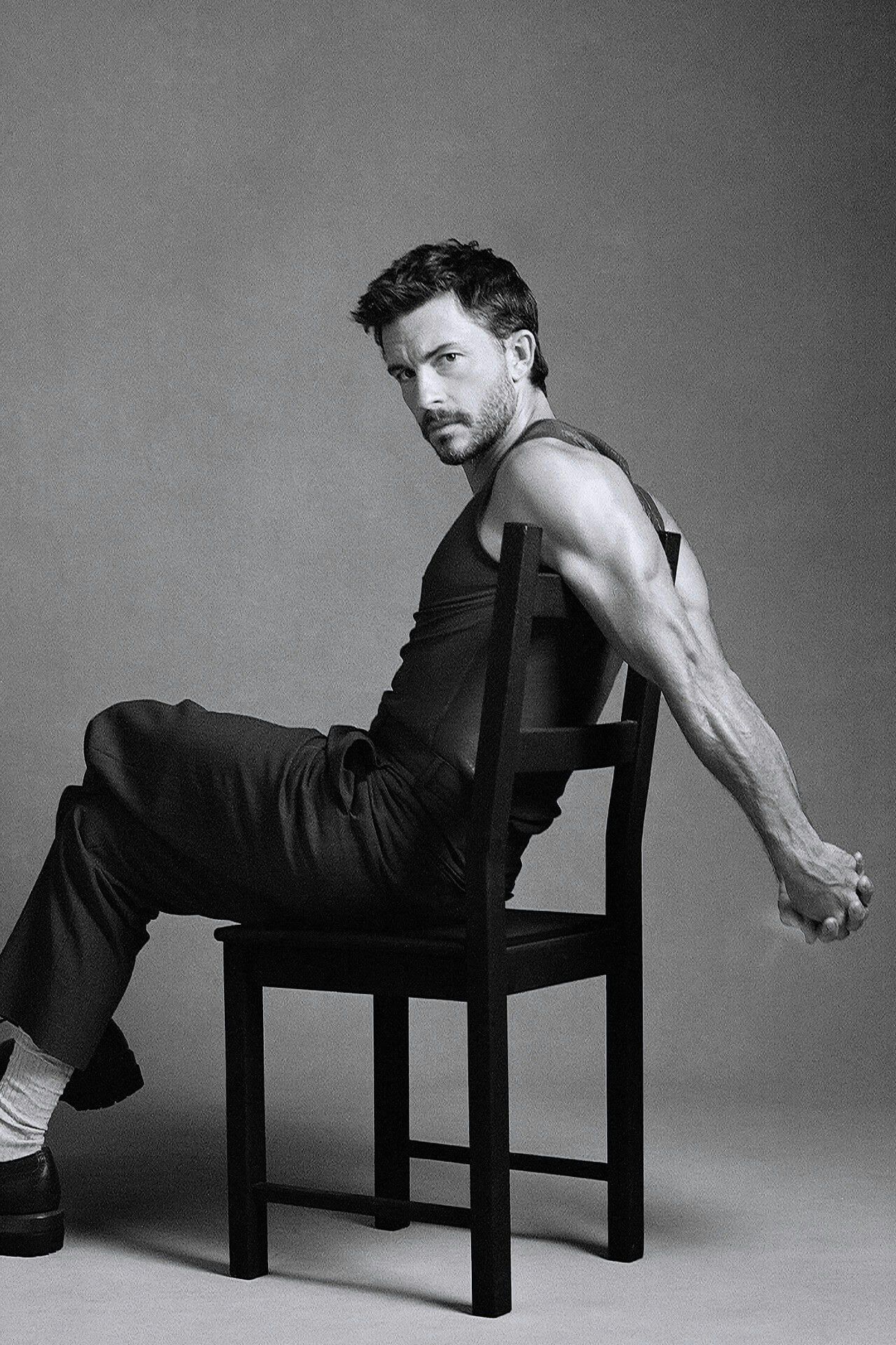 people-man-A-black and white-A-seated on chair-A-tank top-B-muscular arms-C