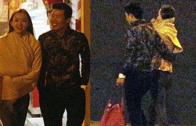people-woman smiling in yellow wrap-man smiling in dark patterned shirt-man carrying baby wrapped in yellow cloth-paparazzi photo style-nighttime outdoor setting