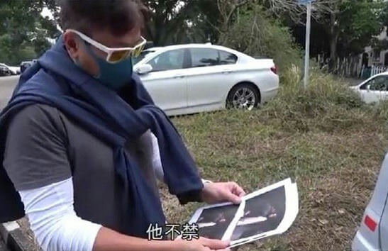people-man-holding photos-A-clothing-blue sweater and white long-sleeve shirt-A-accessories-yellow-lensed sunglasses and face mask-A-setting-outdoor with cars and grass-A-text-Chinese characters 