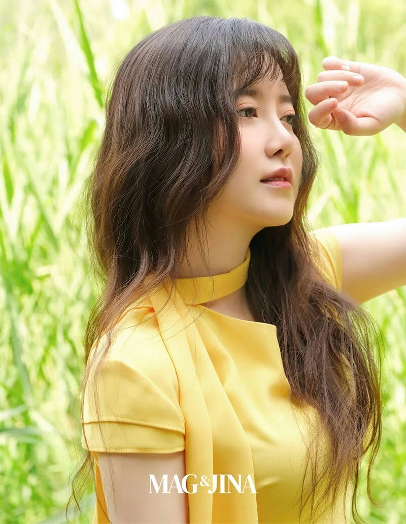 people-woman-A-yellow outfit-A-outdoor setting-A-long brown hair-A-hand shading eyes