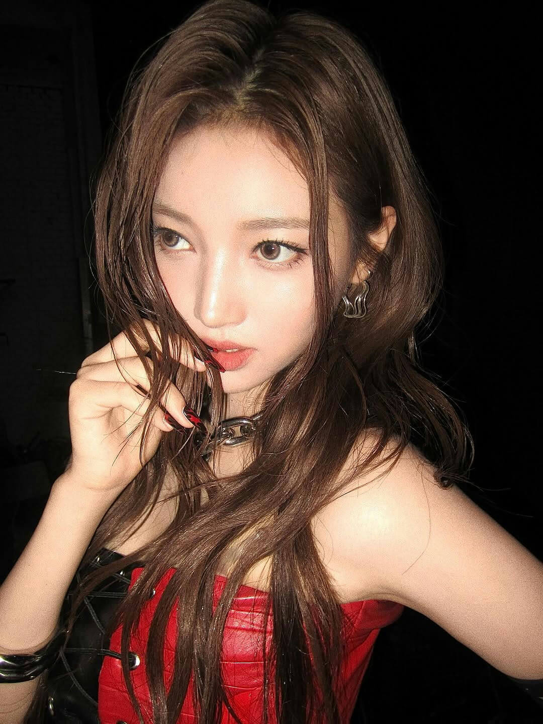 people-woman-A-long brown hair-A-red leather top-B-dark background-C-chain necklace