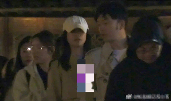 people-woman in white baseball cap-man in light trench coat-woman wearing glasses-person in dark hooded attire