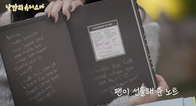 people-A-person holding a notebook-A-black notebook with white handwritten message-B-Korean text overlay at top and bottom-C-hand with dark nail polish