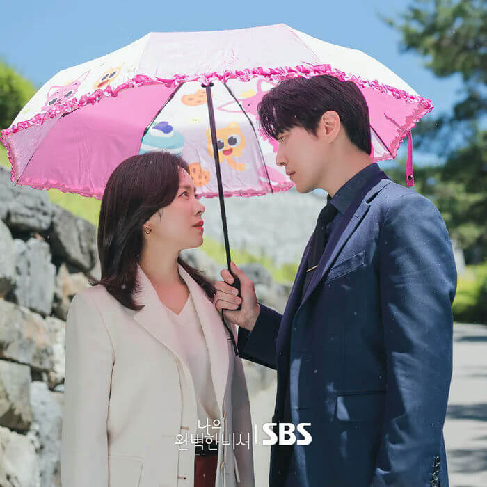 people-A-woman-A-man-A-sharing-an-umbrella-A-looking-at-each-other-A-pink-umbrella-A-outdoor-setting