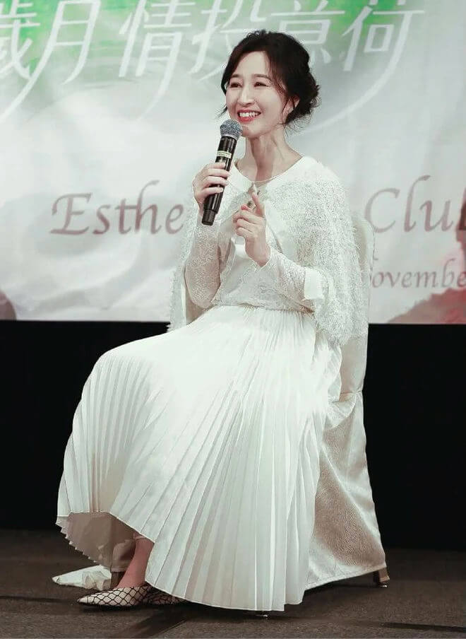 people-woman-smiling-microphone-speaking-white dress-pleated skirt