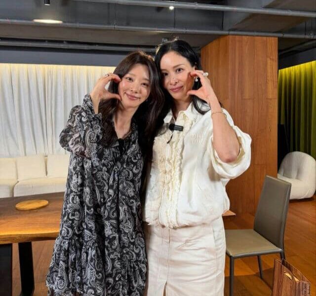 people-Two women-making finger hearts-smiling-posing indoors-wearing stylish outfits