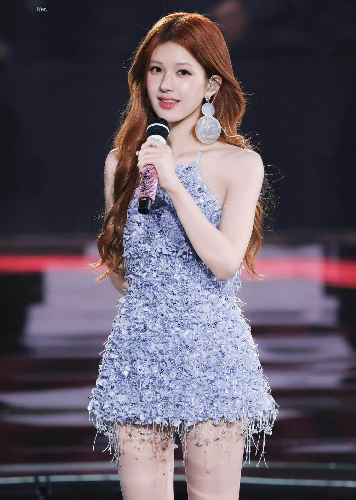 people-woman-holding microphone-performing-long reddish-brown hair-light blue textured mini dress-large circular earrings