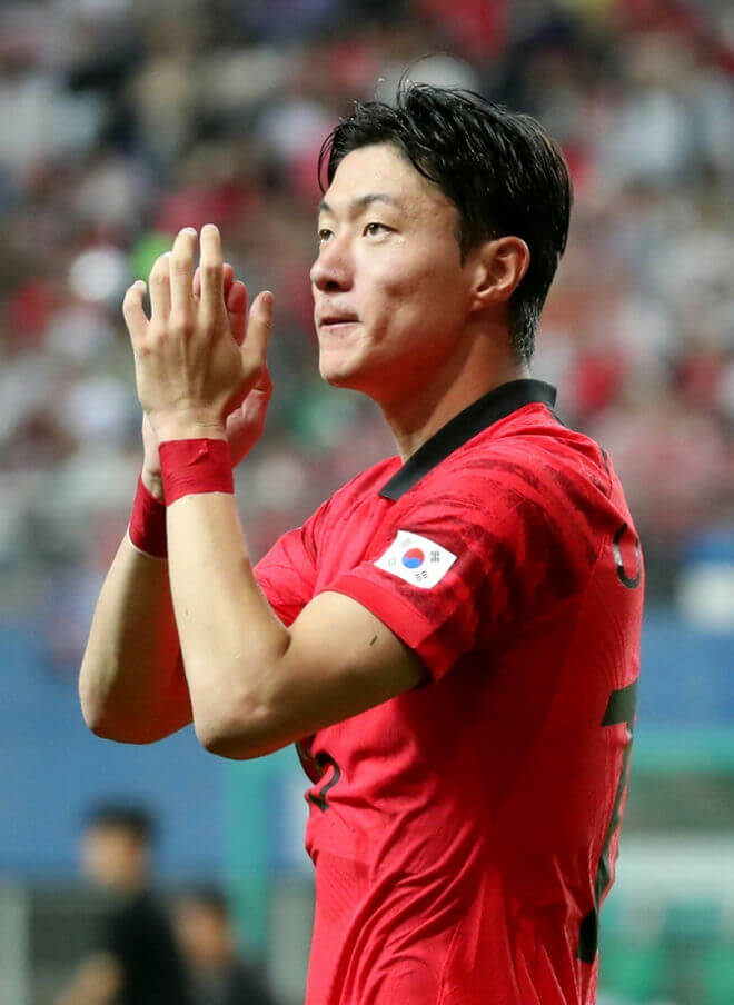 people-South Korean footballer-A-clapping-A-wearing red jersey-A-soccer match-B-audience in background