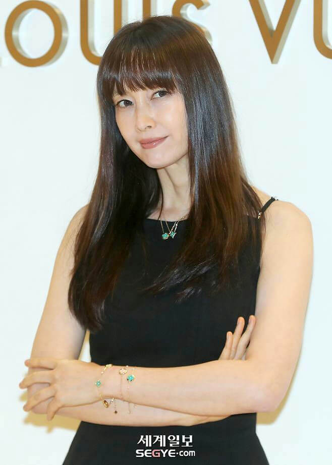 people-Korean actress Kim Hye-soo-black dress-long straight brown hair with bangs-jewelry (necklace and bracelets)-Louis Vuitton background logo