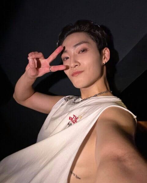people-one male-A-peace sign-A-sleeveless white shirt-B-dark background-C-tattoo