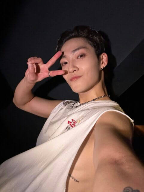 people-one male-A-peace sign-A-sleeveless white shirt-B-dark background-C-tattoo