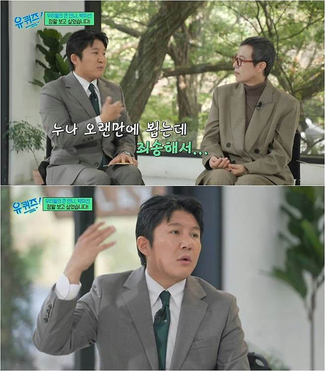people-Two men sitting outdoors or in a bright, natural-light setting-Conversation-Man in grey suit gesturing and speaking-Man in tan suit listening attentively-Korean subtitles present-TV show still