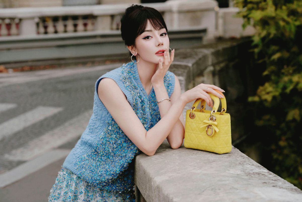 people-A-woman-A-blue-knit-top-A-yellow-handbag-A-outdoor-setting