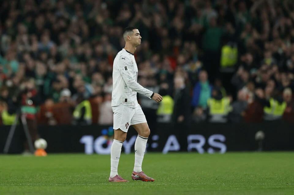 people-Cristiano Ronaldo-A-soccer player-A-walking on field-B-wearing white uniform-C-crowd in background