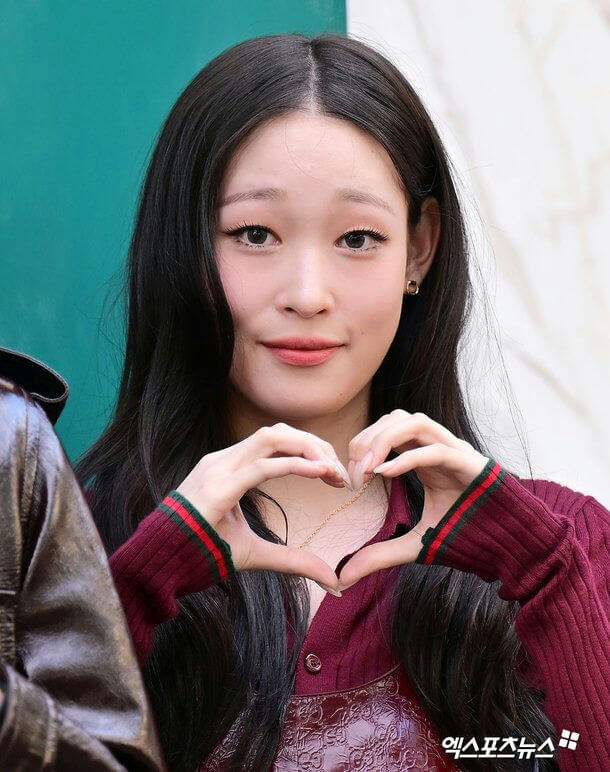 people-A-woman-A-long black hair-B-making heart gesture-C-maroon cardigan