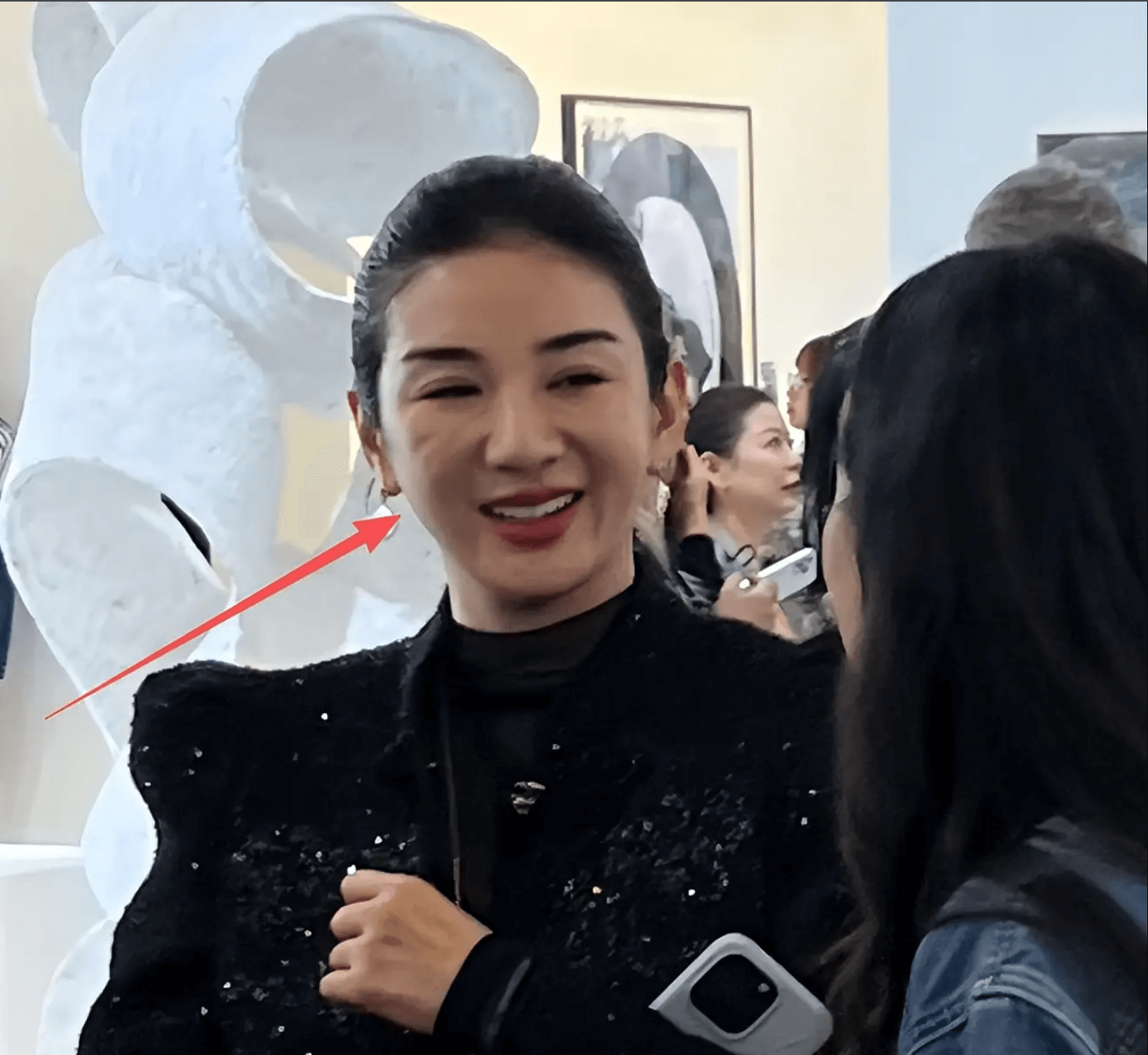 people-woman smiling-A-dark attire-B-crowd background-C-white sculpture