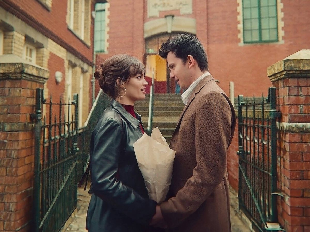 people-A-couple-A-looking-at-each-other-B-holding-flowers-in-paper-C-outside-brick-building