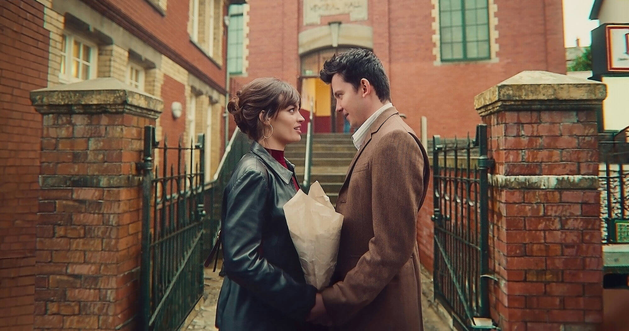 people-A-couple-A-looking-at-each-other-B-holding-flowers-in-paper-C-outside-brick-building