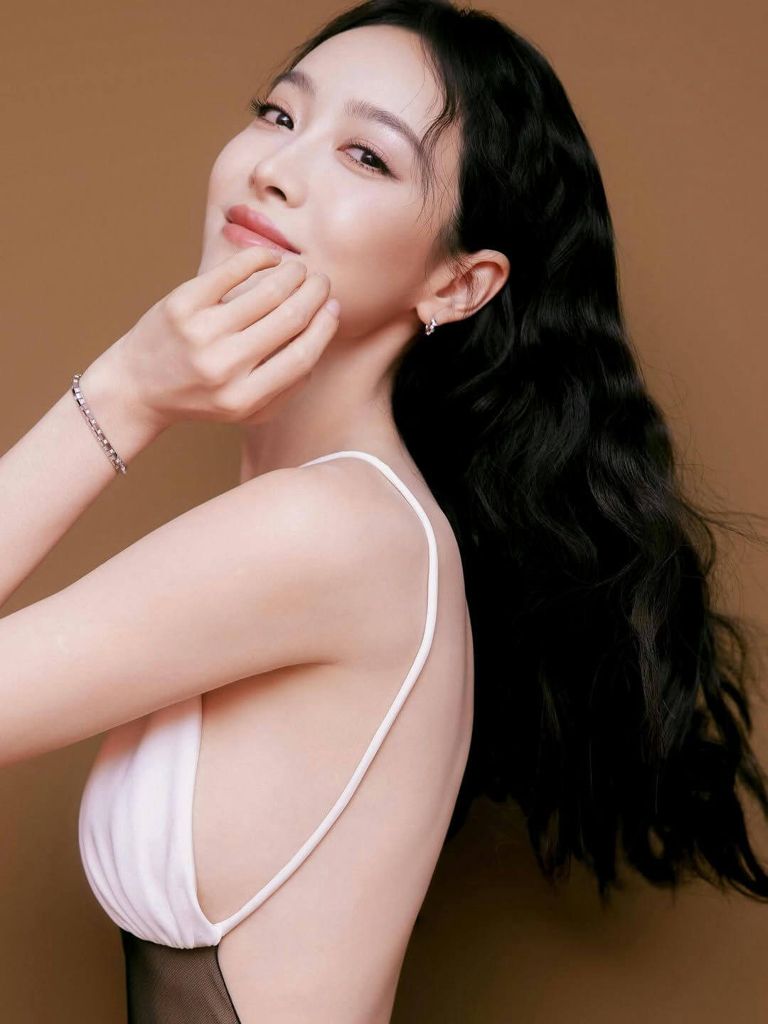 people-Woman-A-black wavy hair-A-white spaghetti strap top-A-bracelet-A-brown background