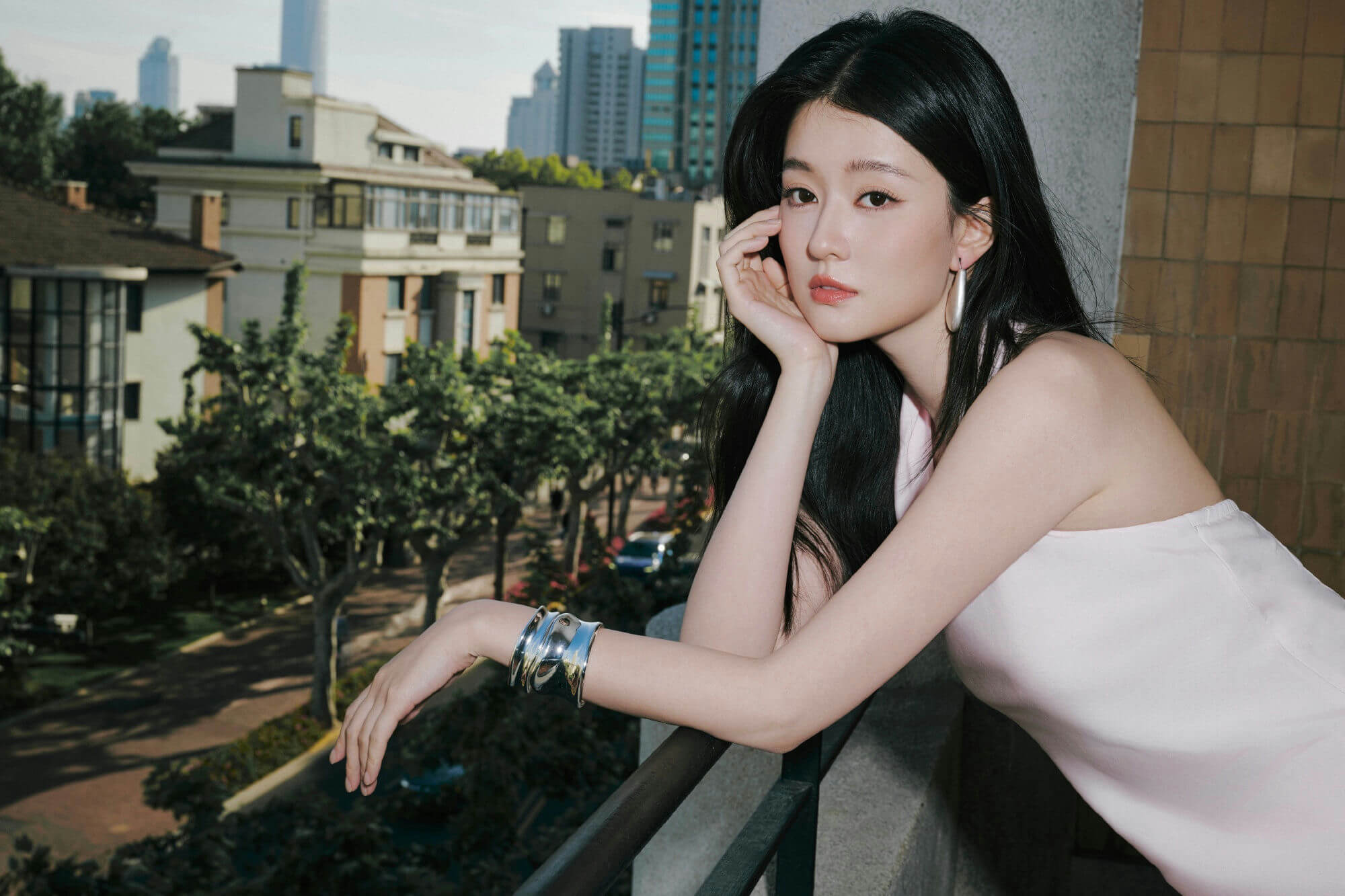 people-A-woman-A-black hair-A-pink top-B-leaning on balcony railing-C-city view