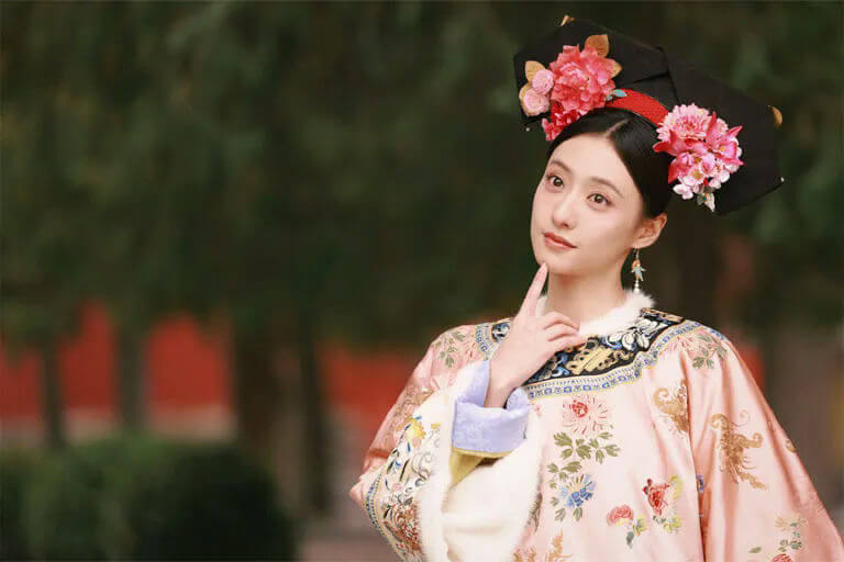 people-A-Chinese actress-A-historical costume-A-Qing Dynasty style-A-pink embroidered robe-A-elaborate headdress-A-outdoor setting