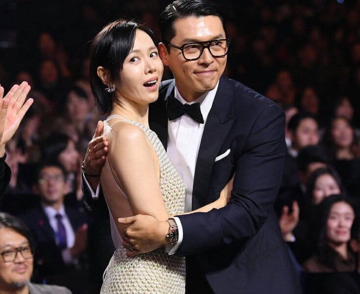 people-woman in sparkling dress-A-man in tuxedo and glasses-B-audience in background-C