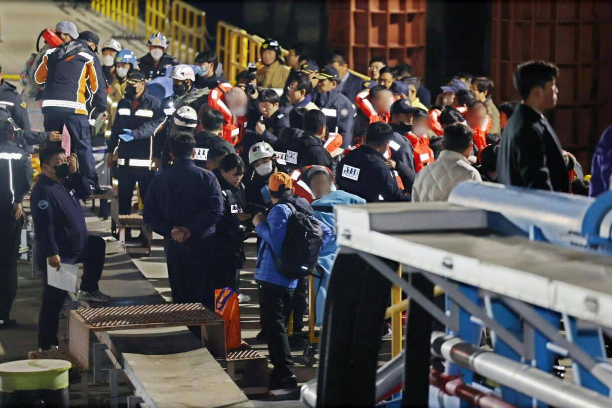 people-Crowd of people-A-Rescue operation-A-Night setting-A-Emergency personnel-B-Life vests-B-Dark uniforms-C-Ramp/gangway-C