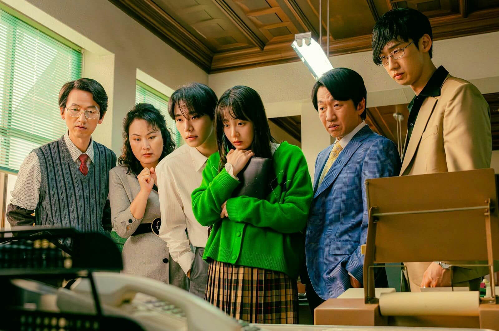 people-6-office-A-serious-A-group-A-concern-A-bright-green-cardigan-A-plaid-skirt