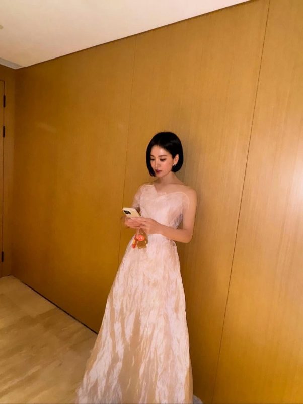 people-A-woman-A-short black hair-A-pink gown-A-holding smartphone-A-indoor