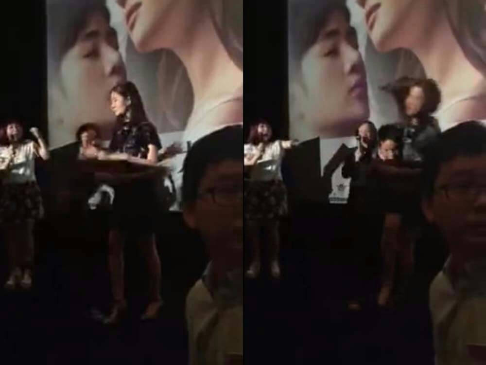 people-Woman speaking at podium-Auditorium stage-Movie poster backdrop-Audience members