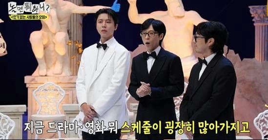 people-Three men dressed formally-A-One man in white tuxedo-B-Two men in black tuxedos-C-Korean variety show set with statues in background