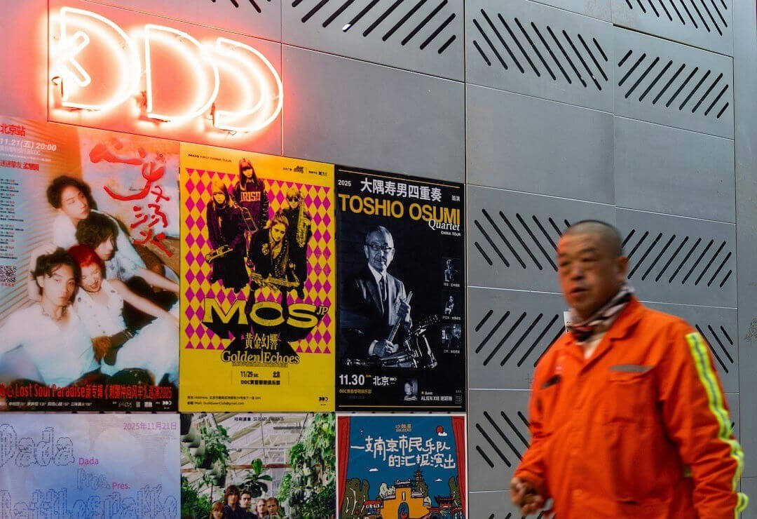 people-man in orange jumpsuit-A-posters on wall-B-neon sign 'DDD'-C-slotted metal panels