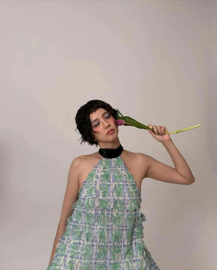 people-woman-A-short black hair-A-green and blue ruffled halter dress-A-holding purple tulip to face-A-black choker necklace
